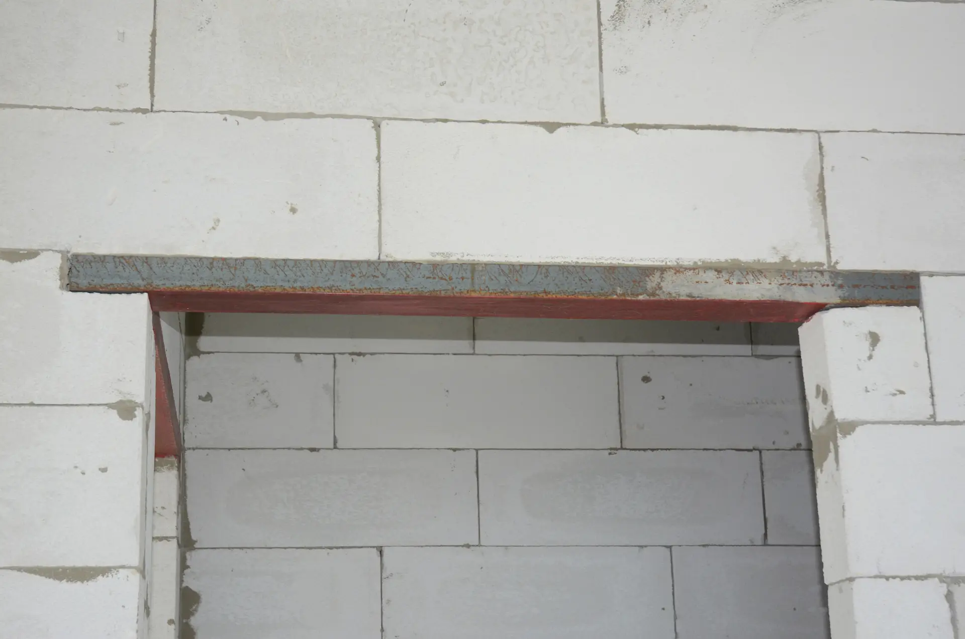 A newly installed metal lintel above a doorway in a masonry wall.